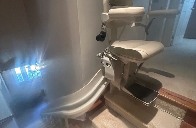 Bruno curved stairlift on a rail turning around the bottom of a carpeted staircase