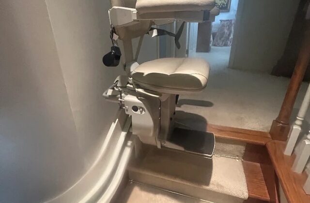Bruno curved stairlift parked at the bottom turn of carpeted stairs beside a doorway