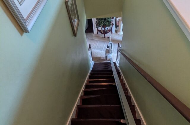 Bruno Elan stairlift rail on stairs leading down from a pale green hallway