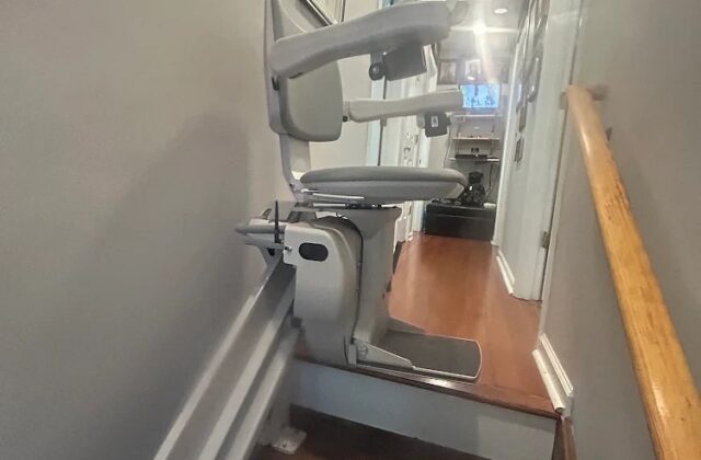 Bruno stairlift on a straight rail down a narrow staircase from an upstairs hallway