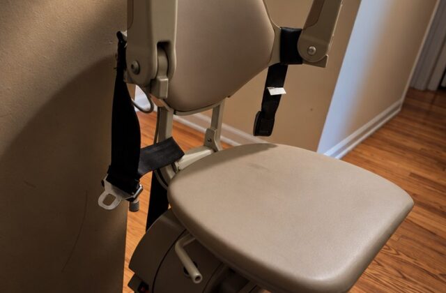 Bruno stairlift at the top of the stairs with the seat folded up and arms raised