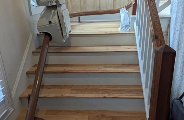 Handicare stairlift rail up light wooden stairs to a landing with a white banister