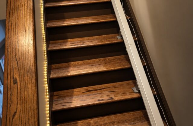 Handicare stairlift rail running up wooden stairs with a light strip along the step edges