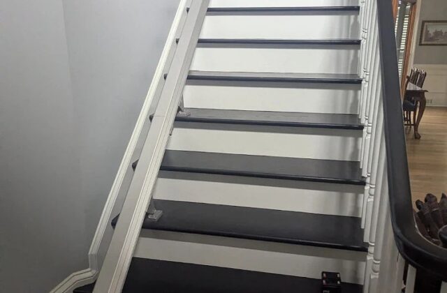 Handicare stairlift rail on a long staircase with white risers and dark treads