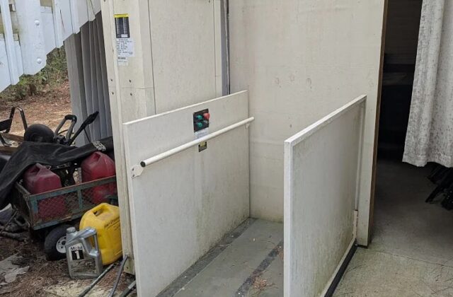 Harmar vertical platform lift beside a deck, its enclosure door open onto the platform