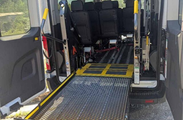 BraunAbility Century wheelchair lift deployed from the rear doors of a passenger van