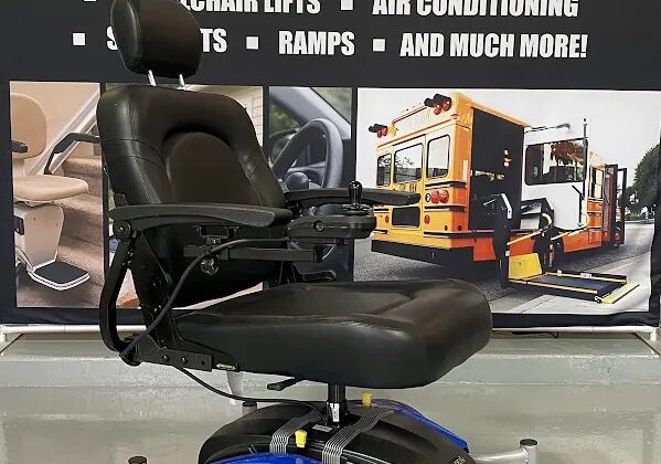 Golden Compass Sport power chair after a repair, in front of a Custom Mobility banner