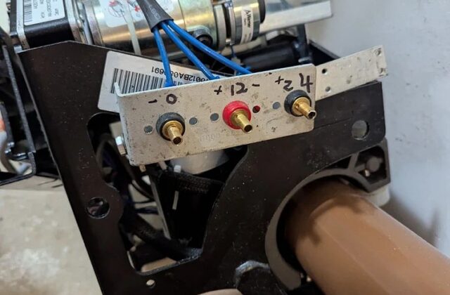 Handicare stairlift drive unit on a curved brown rail, side plate off for service