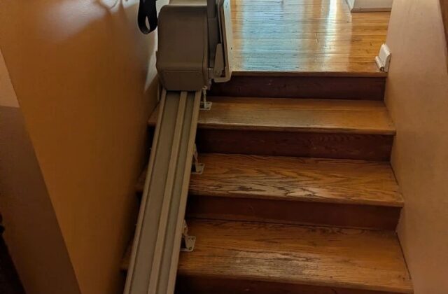 Bruno stairlift parked at the top of a short flight of wooden stairs on a service visit