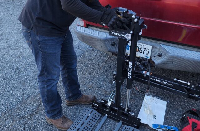 Mason Irby setting up a vehicle lift platform at the back of a red pickup truck